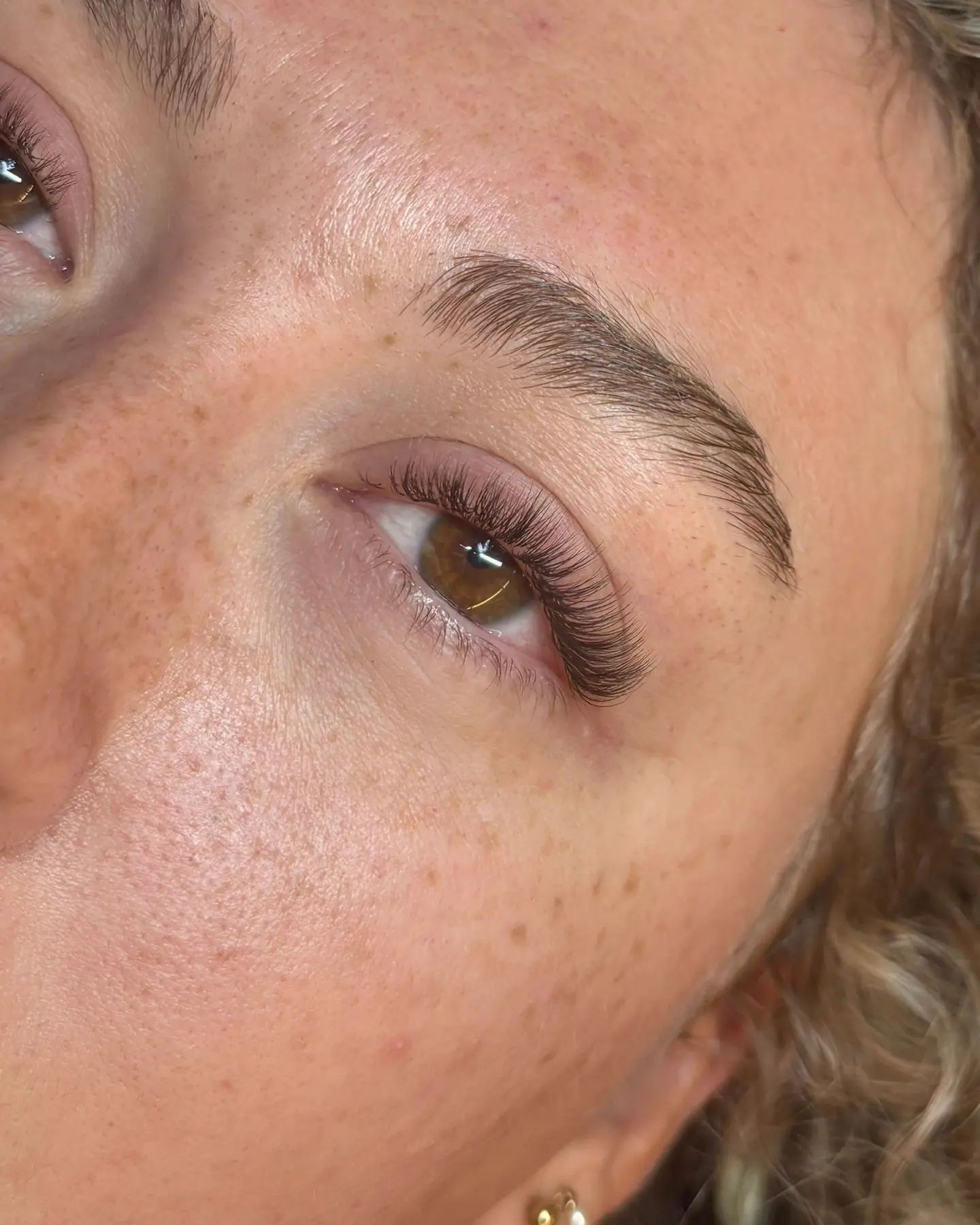 Extensions de cils naturelles sur un regard marron aux taches de rousseur