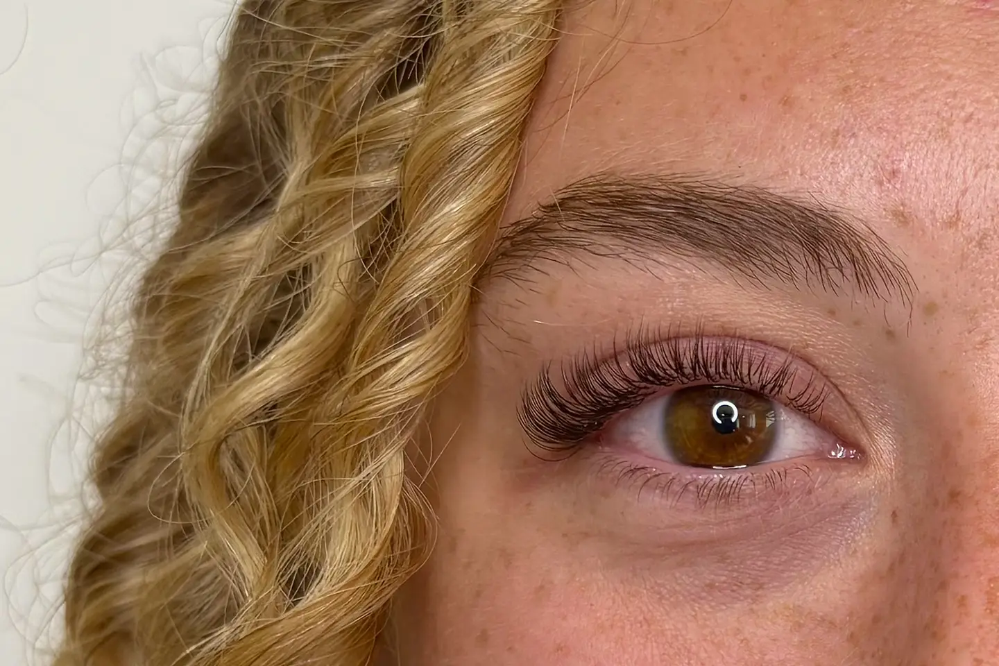 Demi-visage aux cheveux bouclés, extensions de cils au rendu naturel