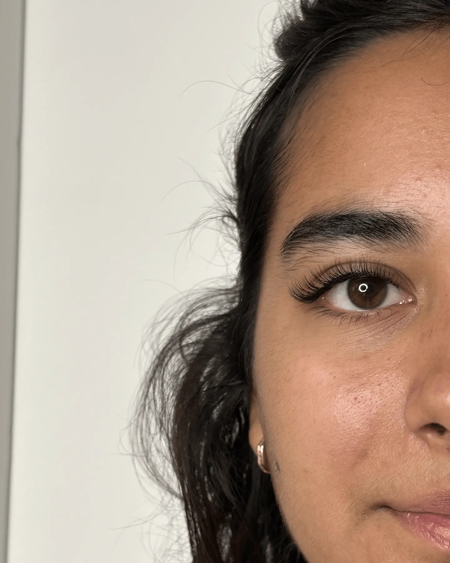Demi-visage aux cheveux bruns, résultat d'une pose d'extensions de cils