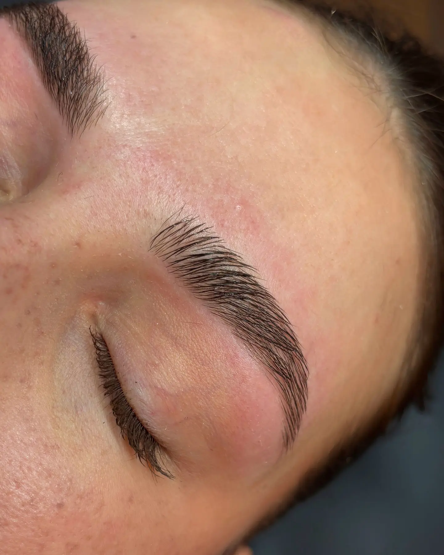 Sourcil restructuré au fil, ligne nette et poils brossés, paupière fermée